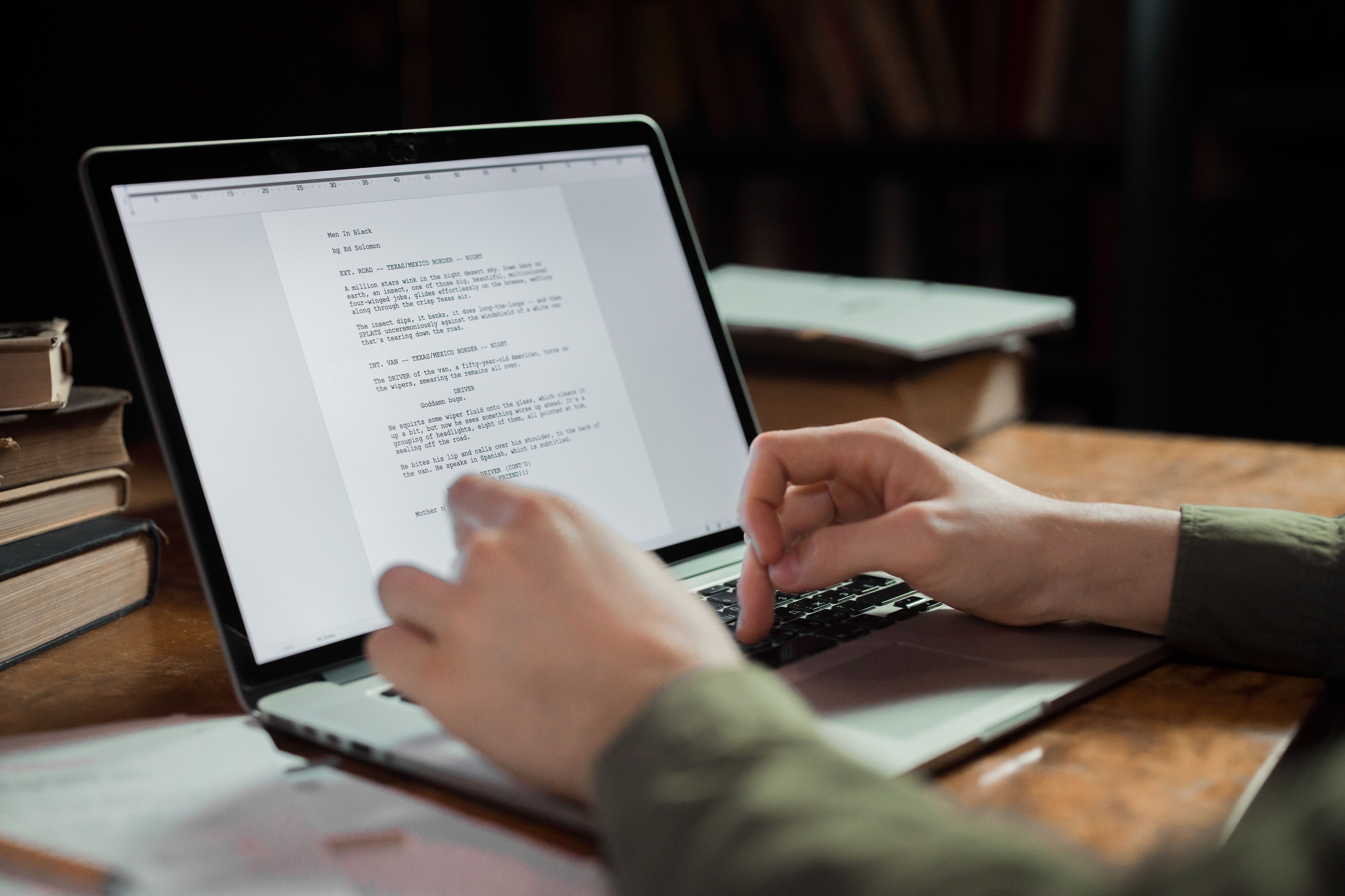 Writer typing on a laptop in a cozy workspace surrounded by books